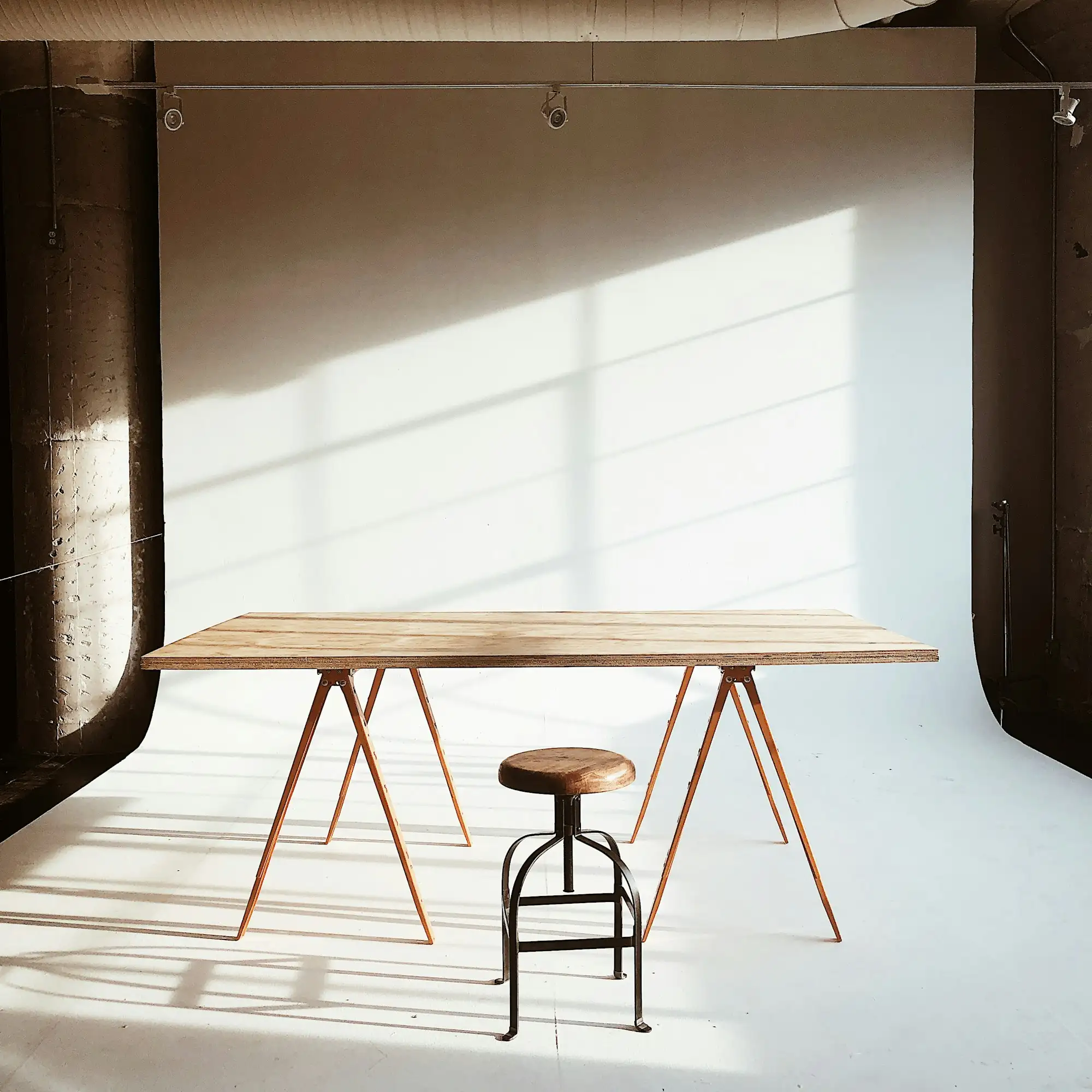 A trestle table and stool in a sunlit studio