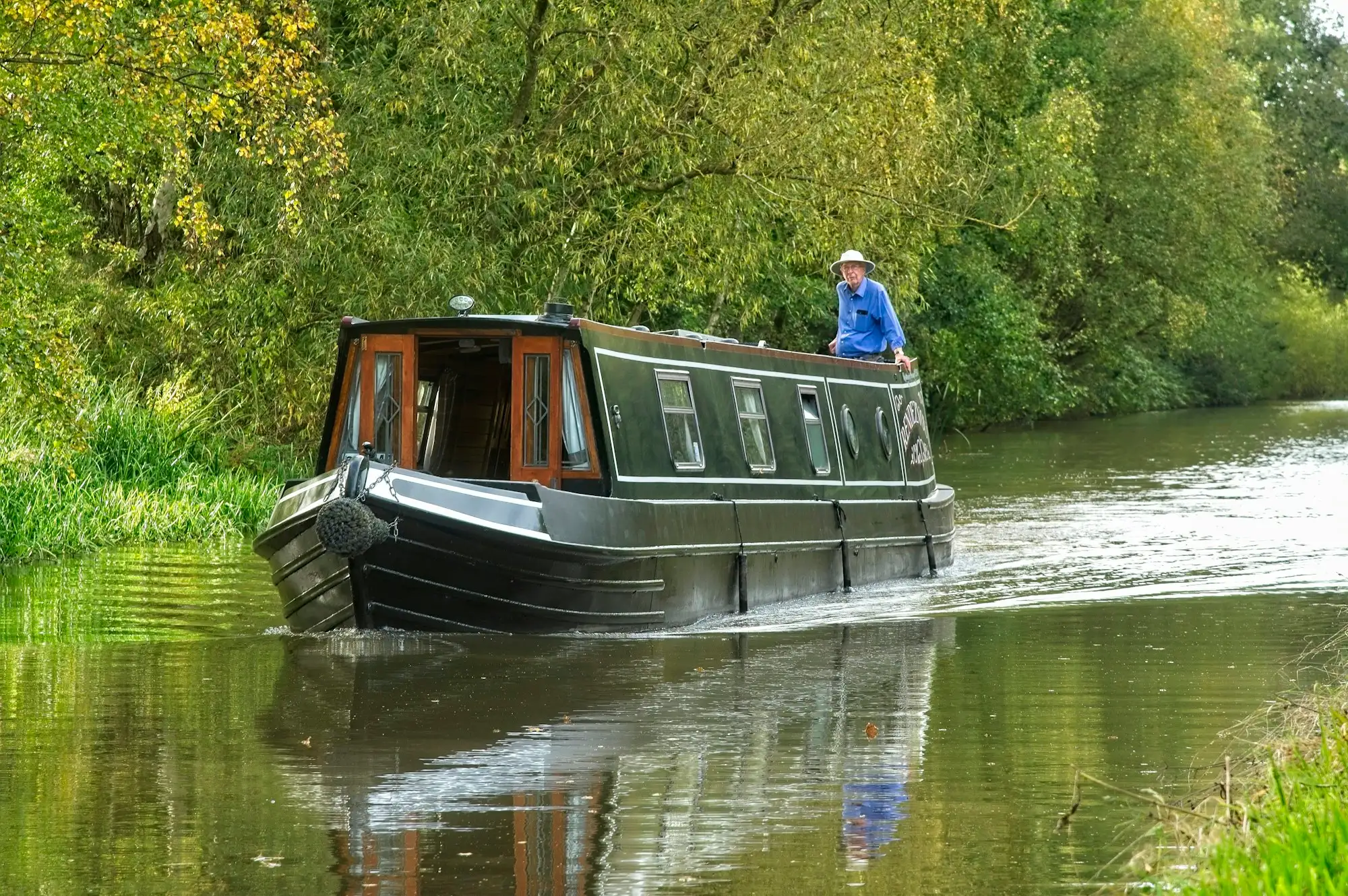 A narrowboat on a tree-lined canal